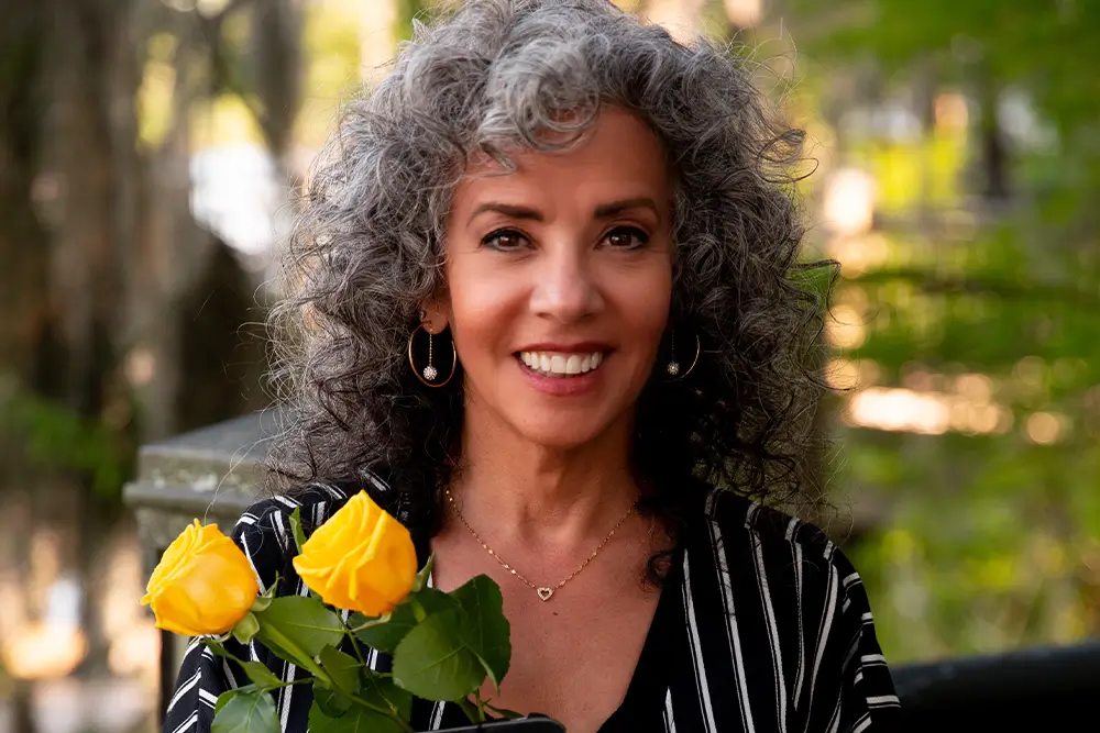 Smiling woman with yellow roses.