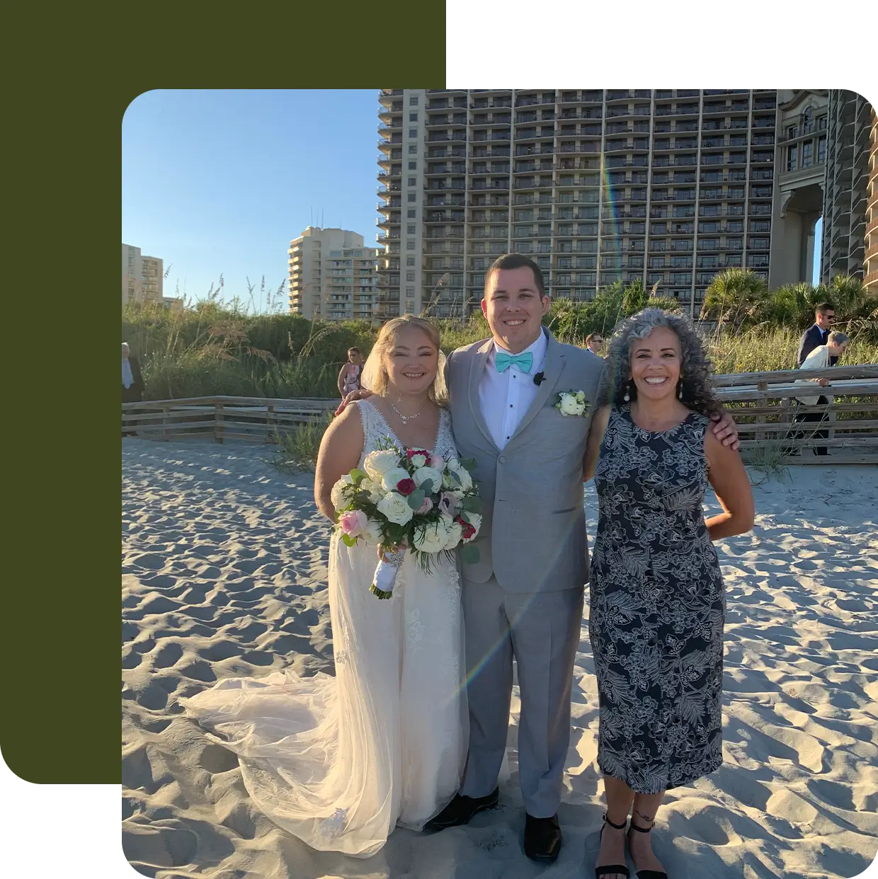 Bride and groom pose with officiant on beach.