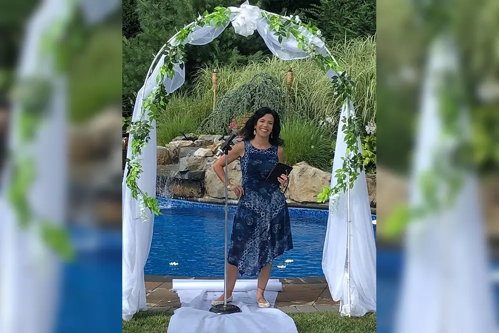 Woman in blue dress by wedding arch.