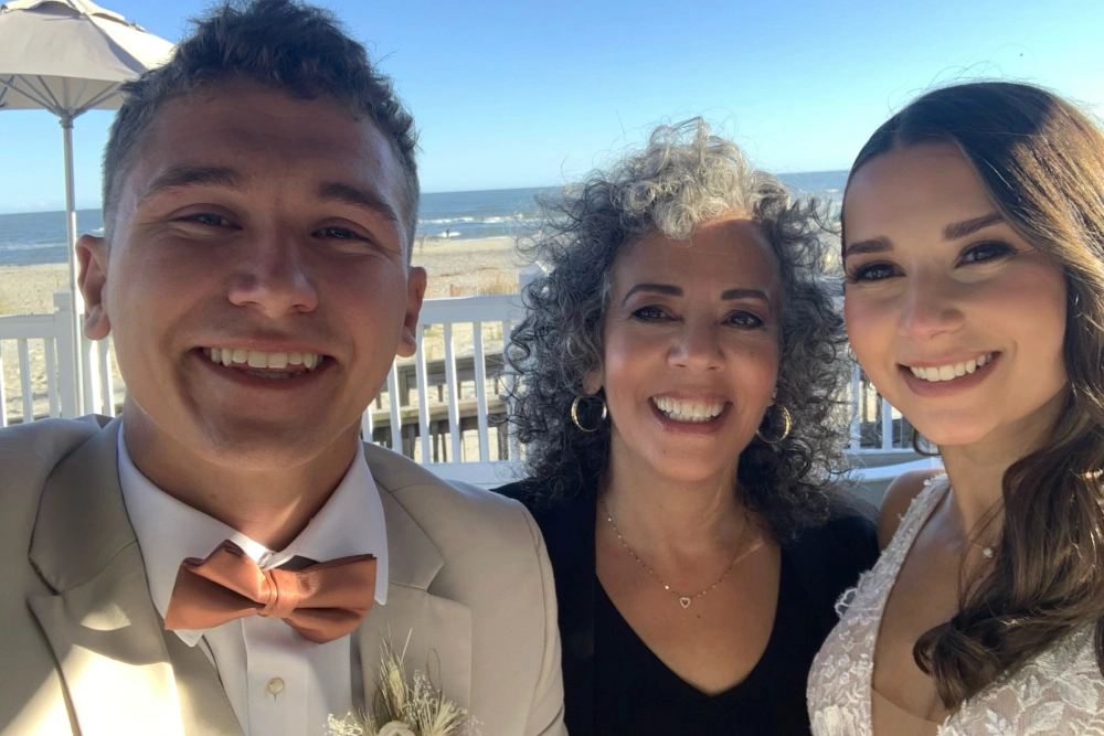 Bride and groom smiling with officiant.