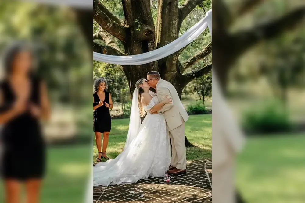 Bride and groom kiss under a tree.