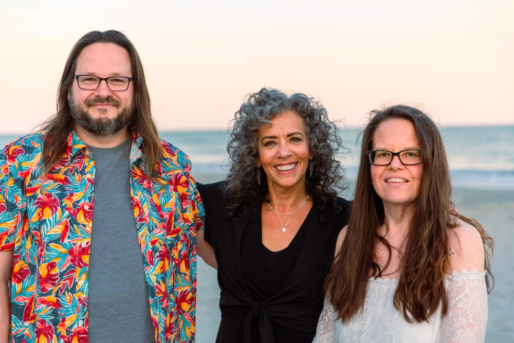 Three friends smiling by the beach.